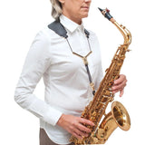 A woman wearing the BG France S73YMSH Zen Yoke saxophone strap and holding a saxophone with it