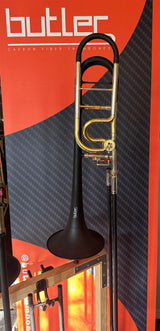 Butler C10 Large Bore Tenor Trombone - resting in a stand with brand poster behind it