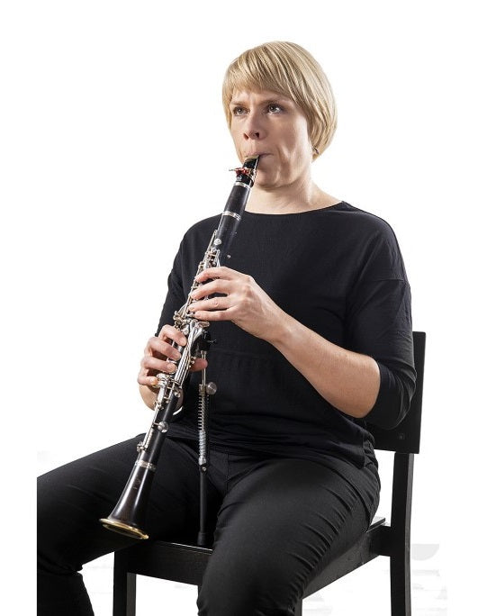 The ERGOclar clarinet support system being used by a woman in a chair playing the clarinet