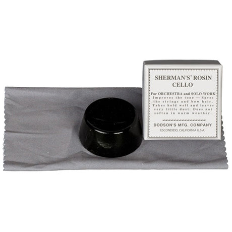 The Sherman Cello Rosin sitting on its silk cloth, that is folded underneath, and it is next to the cardboard package.