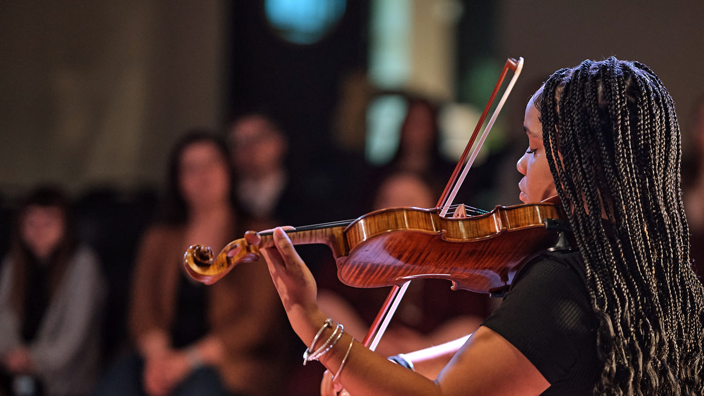 a student playing the violin in an auditorium